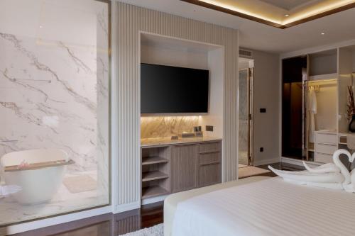 a bedroom with a tv on a wall next to a bed at La Plante Siem Reap in Siem Reap