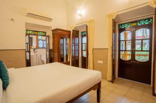 - une chambre avec un lit, une porte et des fenêtres dans l'établissement Alaya Stays Casa do Mar Heritage Portuguese 4 BHK Villa Near Calangute Beach With Private Pool, à Calangute