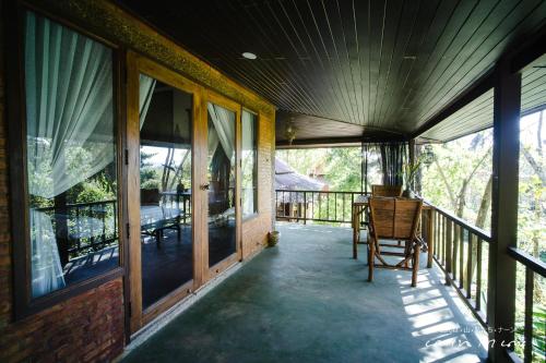 a porch of a house with a chair and windows at บ่อเกลือ วิว รีสอร์ท in Ban Pha Khap