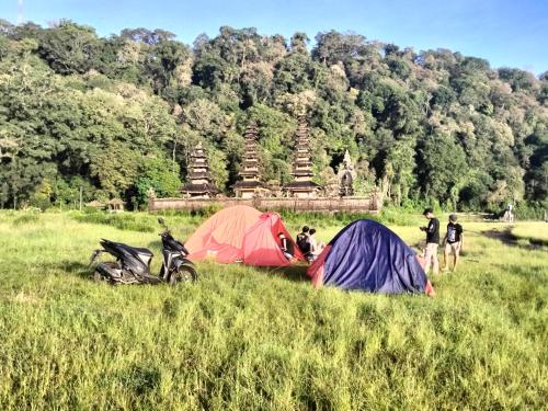 a group of people standing in a field with tents at 3 days jungle trekking adventure tour and camping in Munduk