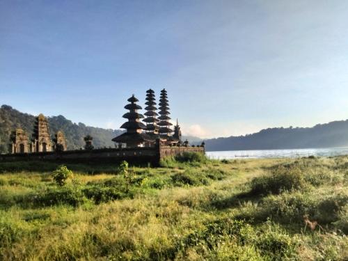 a group of temples in a field next to a body of water at 3 days jungle trekking adventure tour and camping in Munduk
