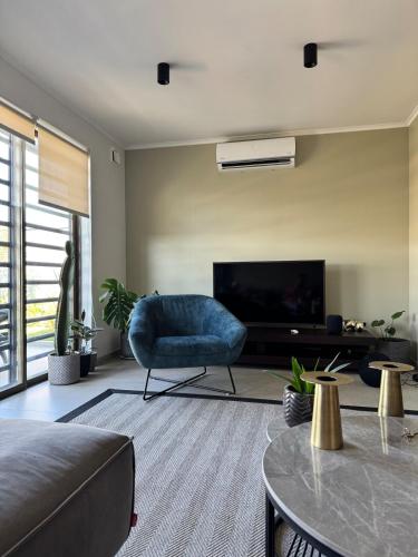 a living room with a blue chair and a television at Linda casa en sector Las rastras Talca in Talca