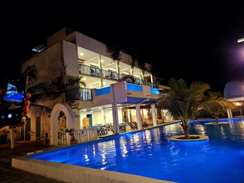 a swimming pool in front of a building at night at Pousada La Grécia in Camocim