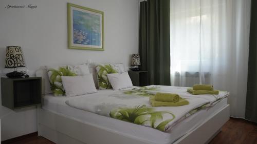 a large white bed with green pillows on it at Apartments Marja in Njivice