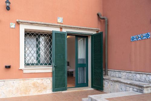 a door with green shutters on a orange building at Al Palmento Relais in Siracusa