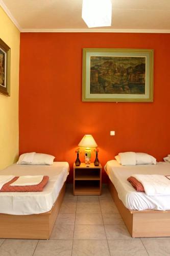 two beds in a room with an orange wall at ODYSSEIA Camping & Bungalows in Katerini