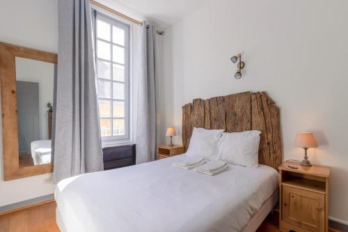 une chambre avec un lit blanc et une grande fenêtre dans l'établissement Appartement de caractère, à Sarlat-la-Canéda