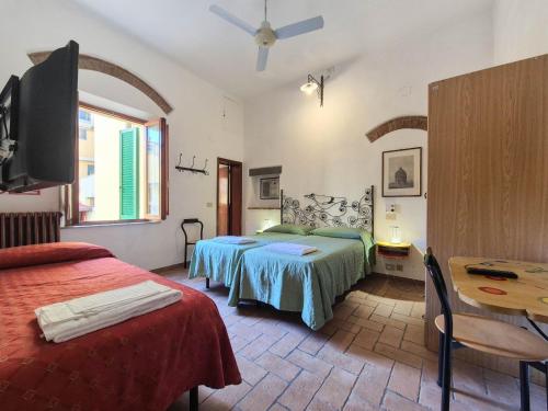 a bedroom with two beds and a table and a tv at Helvetia Pisa Tower in Pisa