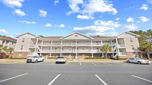 a large apartment building with cars parked in a parking lot at 422 Cypress Bend Condo in North Myrtle Beach