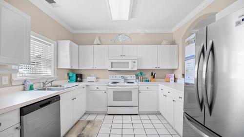 a kitchen with white cabinets and a refrigerator at 422 Cypress Bend Condo in North Myrtle Beach