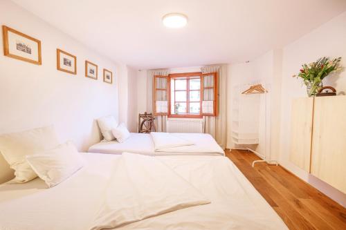 two beds in a bedroom with white walls and wood floors at Apartments No.59 Loket in Loket