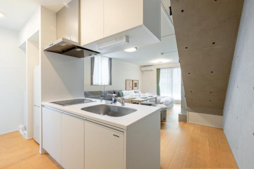 a white kitchen with a sink and a living room at TOKYO SHIBA Retreat 3427 in Tokyo