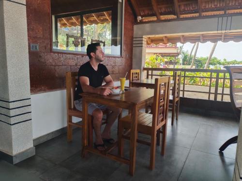 a man sitting at a table in a restaurant at Flower Hill Cottage in Varkala