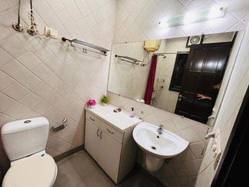 a bathroom with a toilet and a sink and a mirror at Abode Residency near USA Embassy Delhi Safdarjung Enclave New Delhi in New Delhi