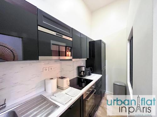 une cuisine avec des armoires noires et un comptoir blanc dans l'établissement 05 - Parisian Design Loft, à Paris