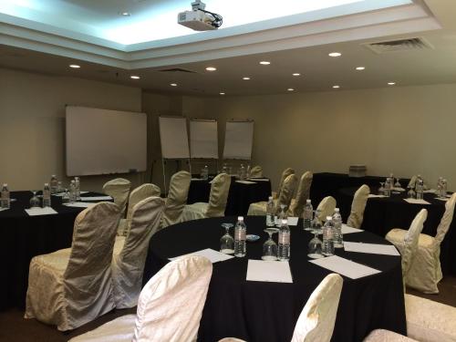 a conference room with tables and chairs and a screen at The Saujana Kuala Lumpur in Subang Jaya