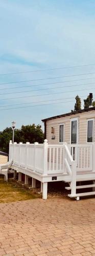a house with a white porch and a white fence at Caravan in Rockley Park 3 Bedrooms in Poole