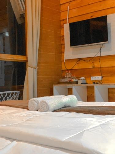 a bed with two rolled towels and a television at Avana Cabin Sikunir Lake View in Kejajar