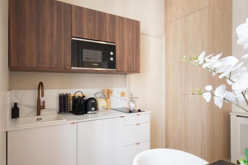 - une cuisine avec un four micro-ondes au-dessus d'une armoire blanche dans l'établissement Pick A Flat's Apartments in Opéra- Rue Saint-George, à Paris