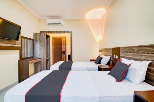 two beds in a hotel room with a tv at Collection O Pusat Kota Pekanbaru Near Rumah Sakit Prima Formerly King's Homestay in Pekanbaru