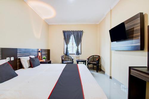 a hotel room with a large bed and a television at Collection O Pusat Kota Pekanbaru Near Rumah Sakit Prima Formerly King's Homestay in Pekanbaru