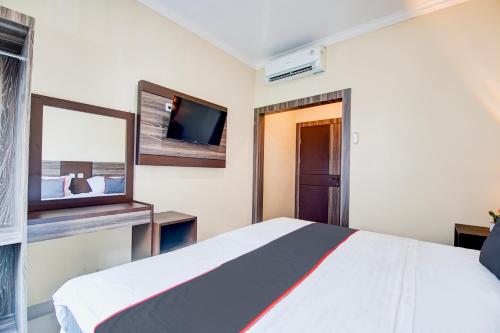 a bedroom with a bed and a flat screen tv at Collection O Pusat Kota Pekanbaru Near Rumah Sakit Prima Formerly King's Homestay in Pekanbaru