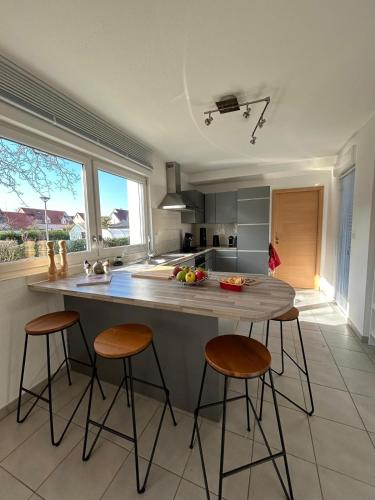 une cuisine avec un grand îlot avec quatre tabourets de bar dans l'établissement Au Coin du Verger, à Colmar