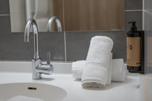 a bathroom sink with towels and a faucet at Hôtel Restaurant Oberlé in Kilstett