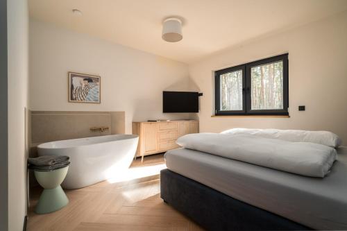 een slaapkamer met een bed, een bad en een televisie bij Waldvilla Haus Gustav am Ostseestrand in Lubmin