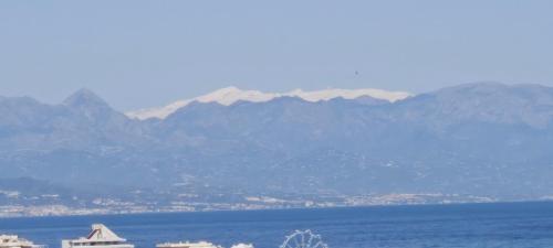 a view of the ocean with mountains in the background at Rooms Flor del Pato in Benalmádena