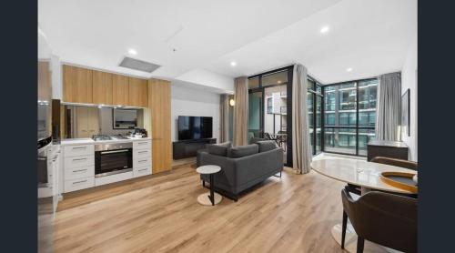 eine Küche und ein Wohnzimmer mit Sofa und Tisch in der Unterkunft CBD Resort with King Suite, Pool, Gym, Sauna, Cafe, Wifi, IGA in Adelaide