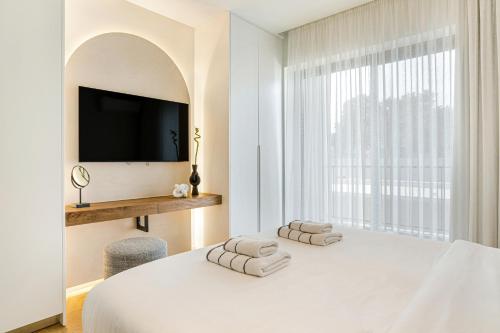 アギオス・ニコラオスにあるUrban Height Suitesの白いベッドルーム(ベッド1台、壁にテレビ付)