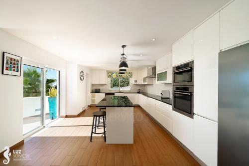 a white kitchen with a counter and a table at 180 degree Ocean Views, Pure Paradise in Luz
