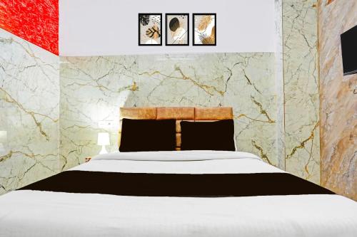 a bedroom with a white bed and a marble wall at Hotel O Rama Utsav in Gwalior