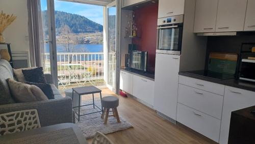 - un salon avec une cuisine offrant une vue sur l'eau dans l'établissement La parenthèse du lac, à Gérardmer