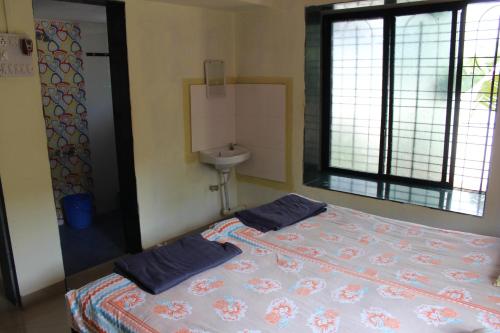 a bedroom with a bed and a sink and a window at Barve Homes in Ratnagiri
