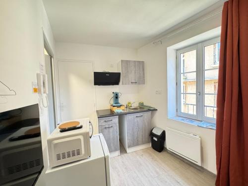Elle comprend une petite cuisine avec un réfrigérateur et une fenêtre. dans l'établissement Petit studio, fonctionnel 2B, à Royat