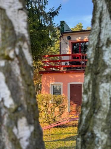an orange house with a red balcony in front of it at Leśna Osada Tęcza Jabłonowiec in Jabłonowiec