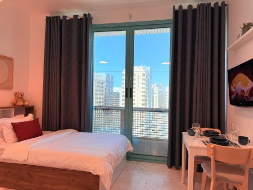 a bedroom with a bed and a desk and a large window at ONE Guest Place Twin Room with Shared Toilet in Abu Dhabi