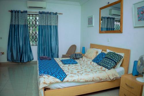a bedroom with a bed with blue pillows and a mirror at Royal London Ville Apartment in Tema Community 6 in Tema
