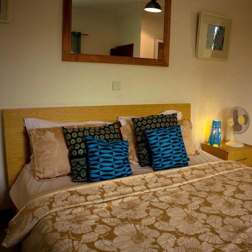a bedroom with a bed with pillows and a mirror at Royal London Ville Apartment in Tema Community 6 in Tema