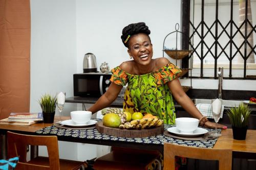a woman standing at a table with a bowl of fruit at Royal London Ville Apartment in Tema Community 6 in Tema