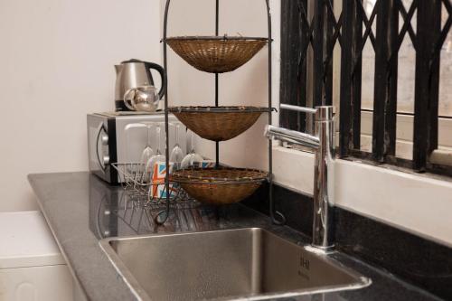 a kitchen counter with a sink and baskets on the wall at Royal London Ville Apartment in Tema Community 6 in Tema
