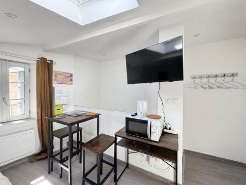 Cette chambre dispose d'un four micro-ondes, d'une table et d'une télévision. dans l'établissement Petit studio, fonctionnel 2C, à Royat