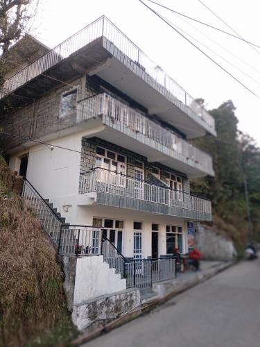 a white building with balconies on the side of a street at Check-in & Chill in Dharamshala