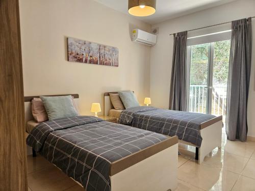 two beds in a room with a window at SeaLine in St. Paul's Bay