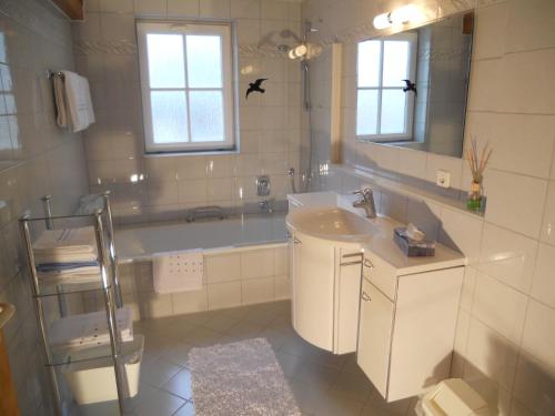 Un baño con bañera, lavabo y espejo. en Ferienwohnung am Kniebach, en Immenstaad am Bodensee