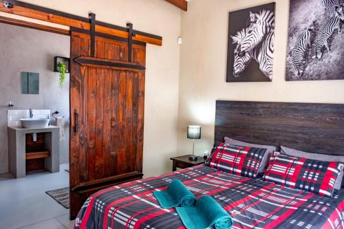 a bedroom with a bed with a wooden headboard and a sink at Die Watergat in Marloth Park