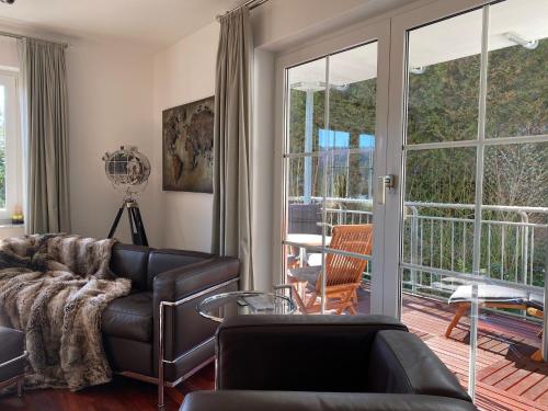 ein Wohnzimmer mit einem Ledersofa und einem Balkon in der Unterkunft Exklusive Ferienwohnungen und Business Apartments Marburg in Marburg an der Lahn