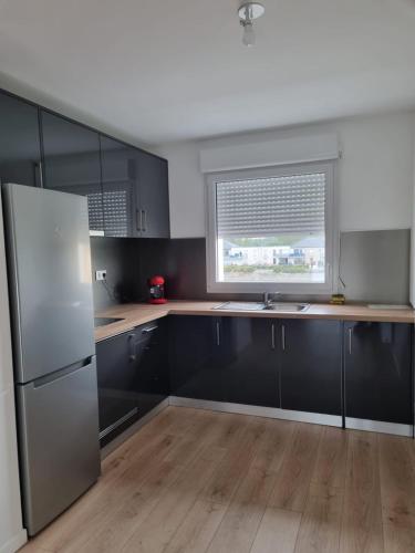 - une cuisine avec des armoires noires et un réfrigérateur blanc dans l'établissement Apartements Dunkerque, à Grand-Fort-Philippe